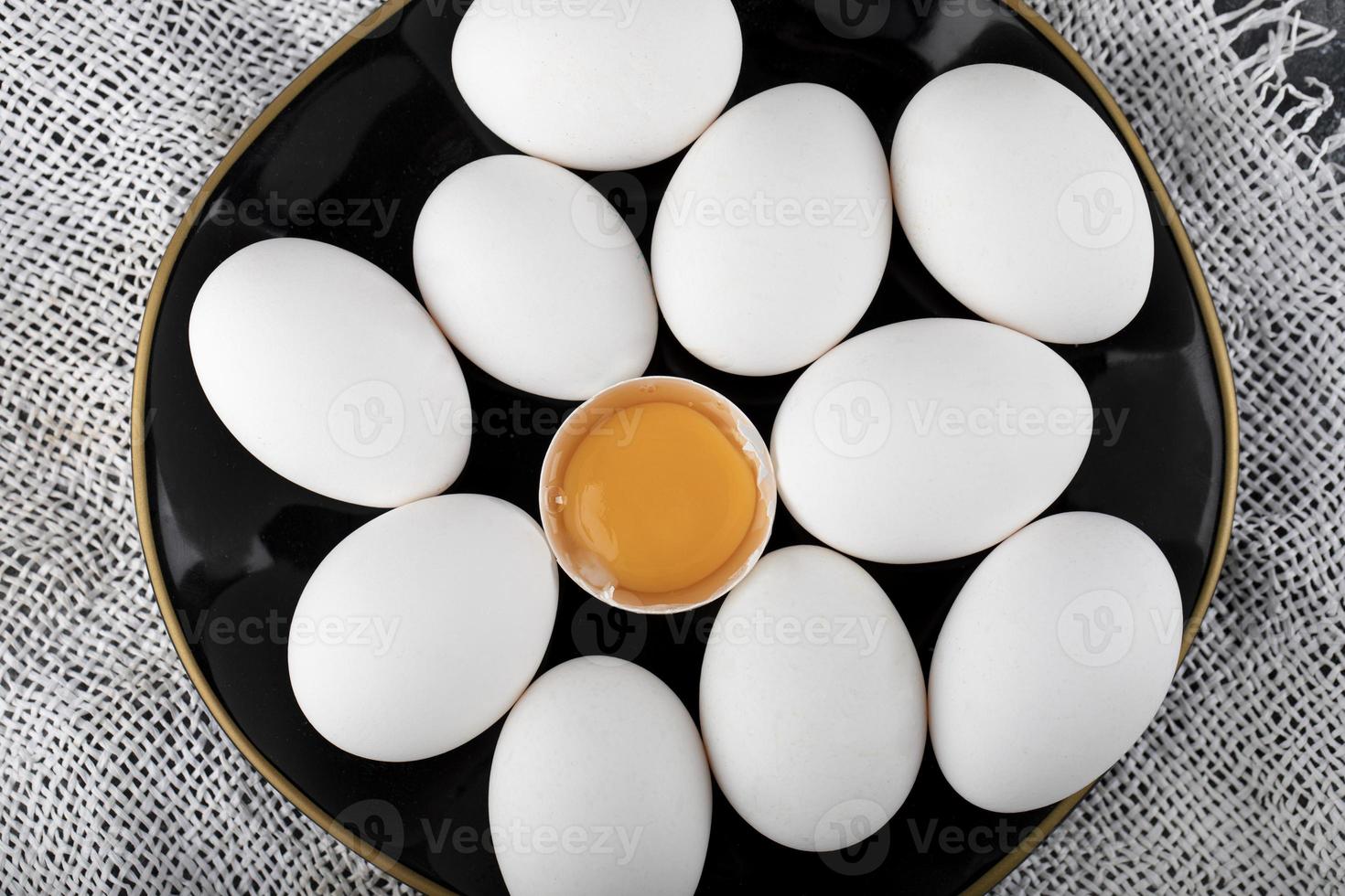 witte eieren en dooier op een zwarte plaat foto