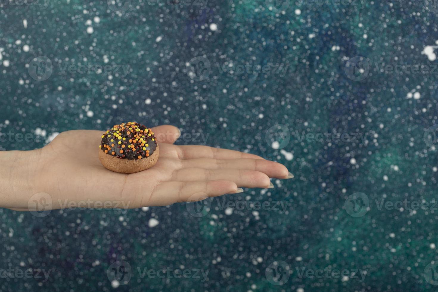 vrouwelijke hand met een koekje op een kleurrijke achtergrond foto