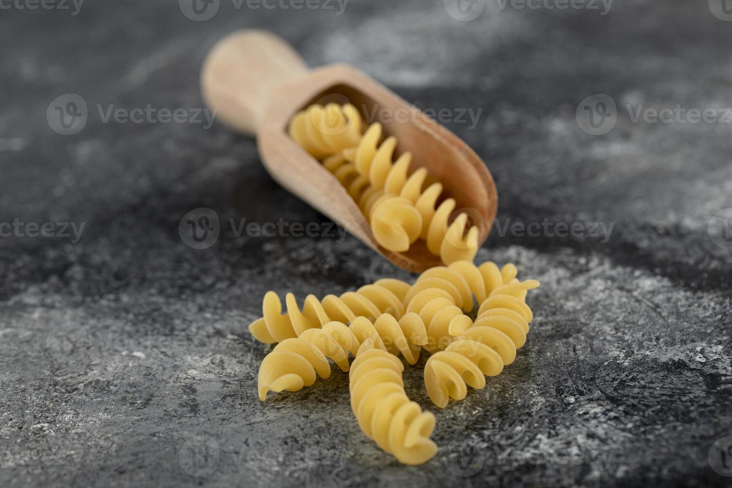 houten lepel rauwe fusilli op een marmeren achtergrond foto