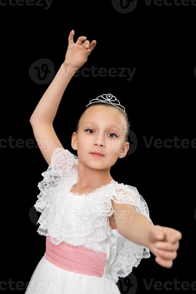 schattig meisje ballerina in wit lang jurk dansen Aan zwart achtergrond in studio. foto