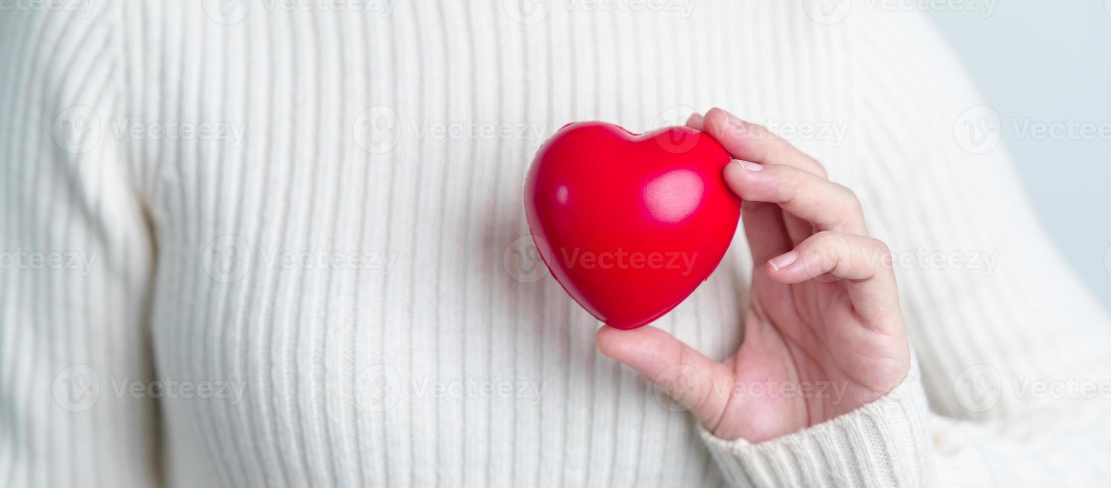 vrouw hand- Holding rood hart vorm geven aan. liefde, schenker, wereld hart dag, wereld Gezondheid dag en verzekering concepten foto