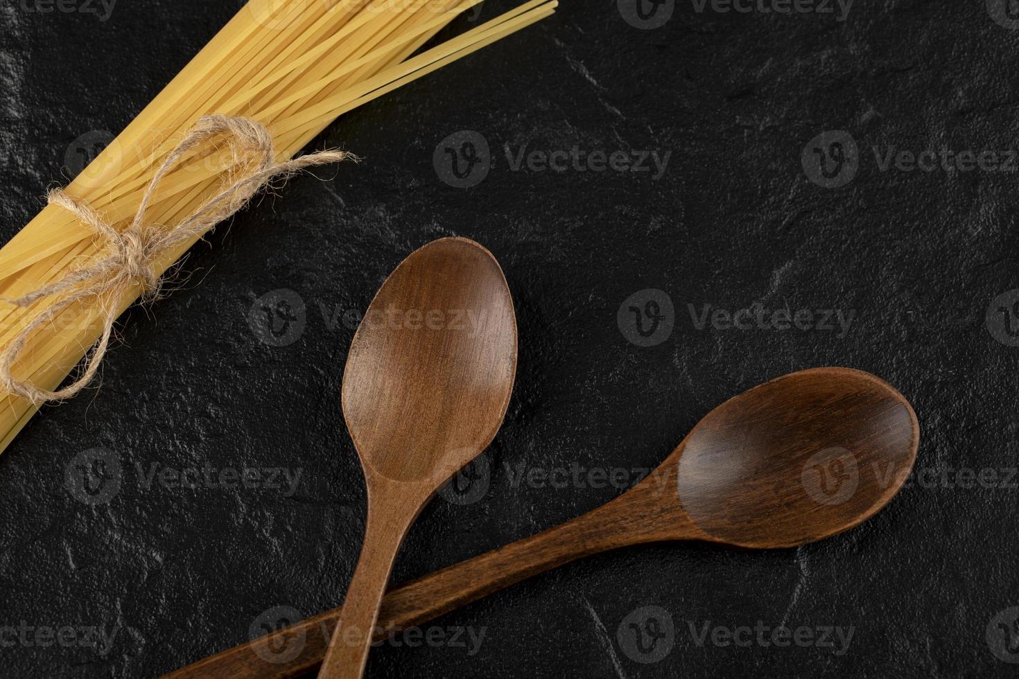 rauwe spaghetti en houten lepels op een zwarte achtergrond foto