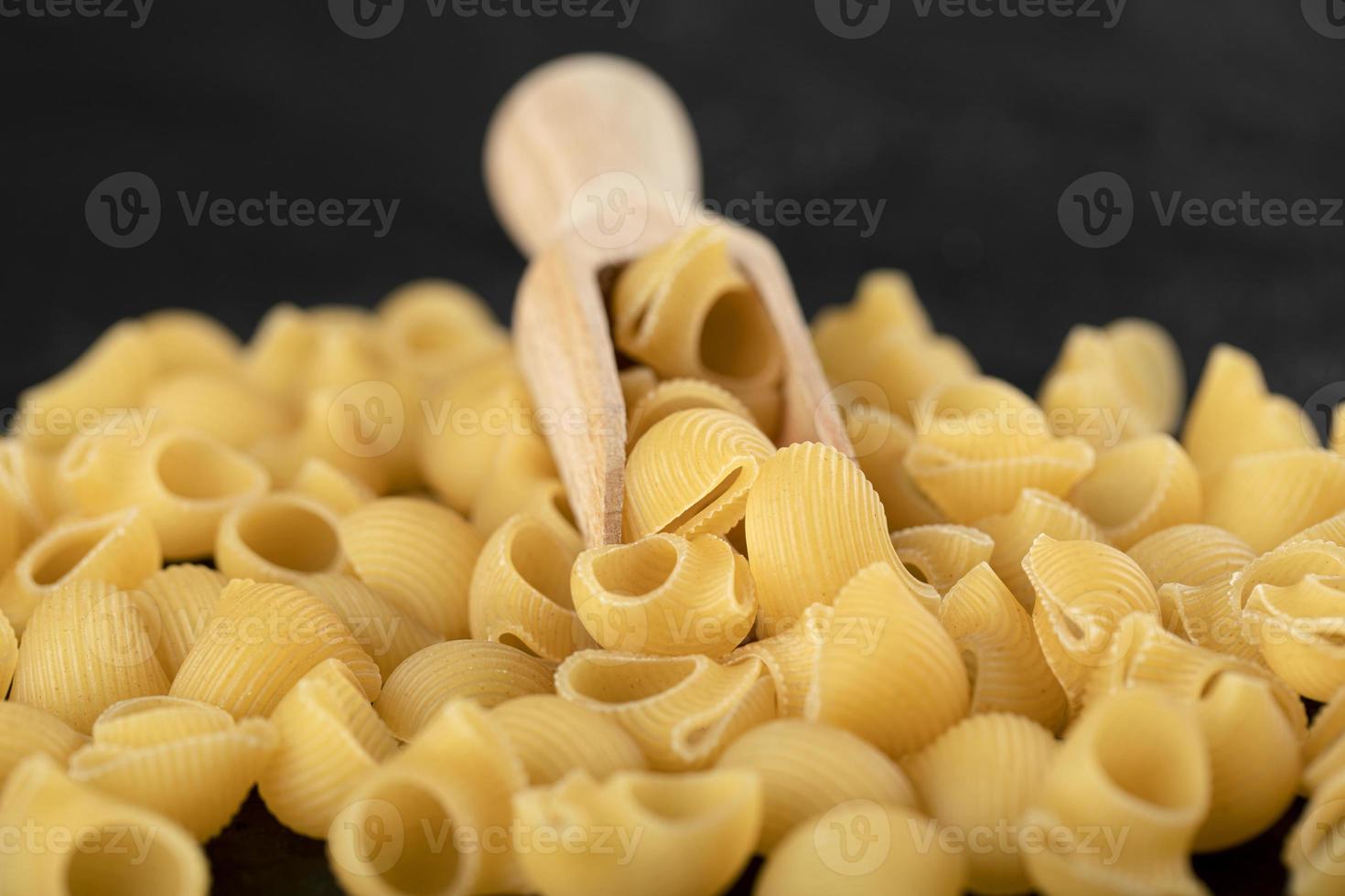 rauwe zeeschelpvormige pasta op een zwarte achtergrond foto