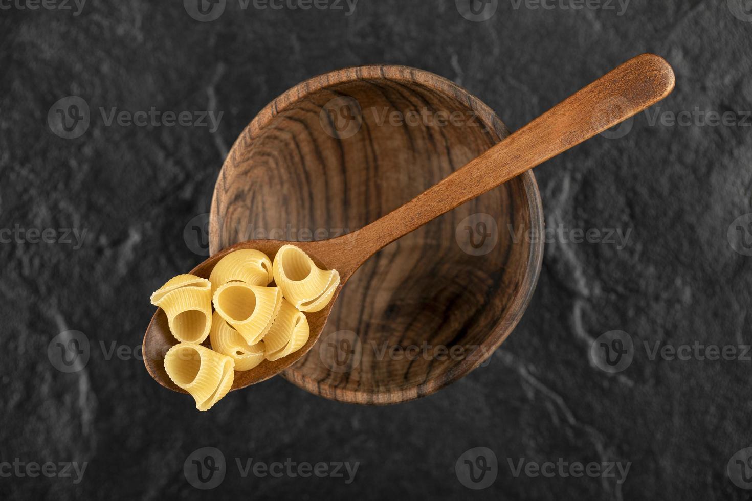 een houten lepel ongekookte conchiglie macaroni foto