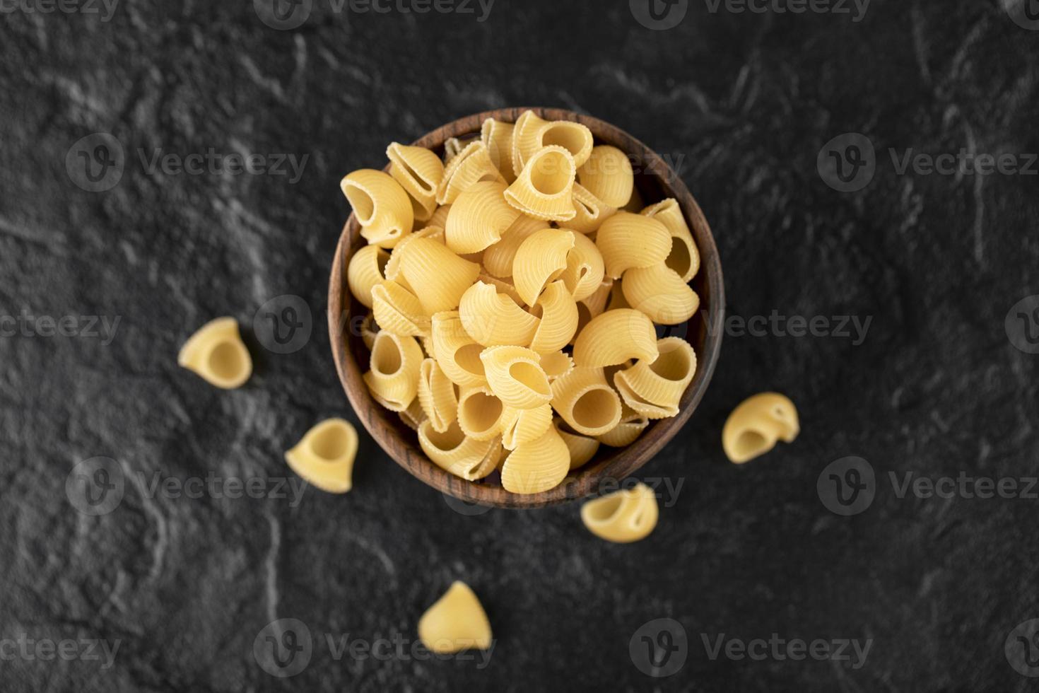 Italiaanse ongekookte pasta conchiglie in een houten kom foto