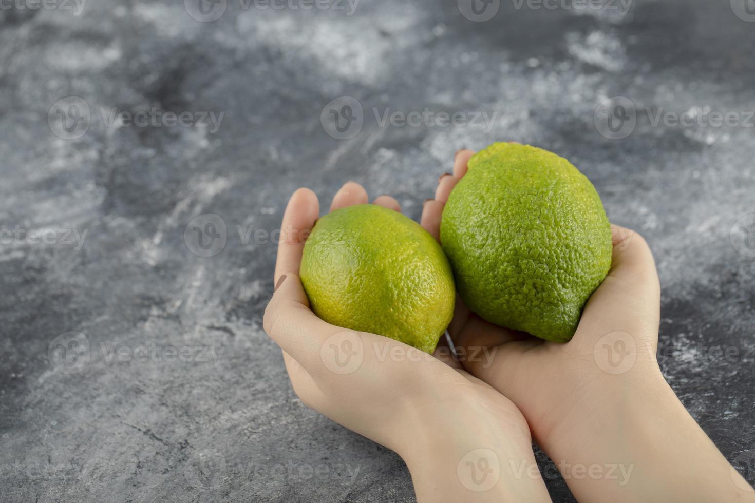 vrouw handen met twee groene verse citroenen foto