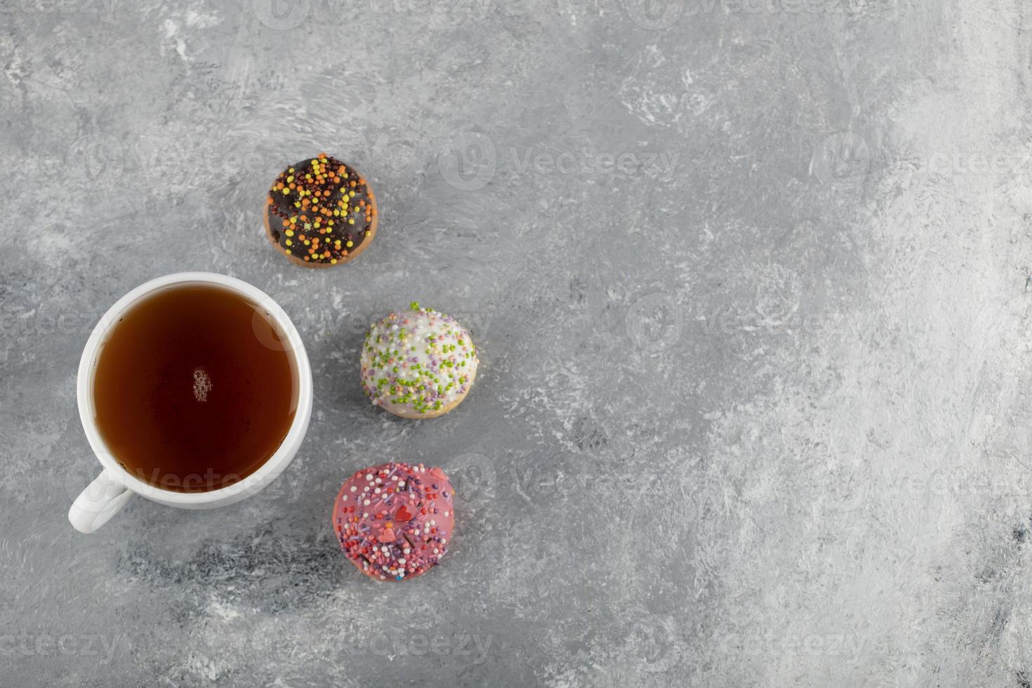 een wit kopje thee met heerlijke kleine donuts foto