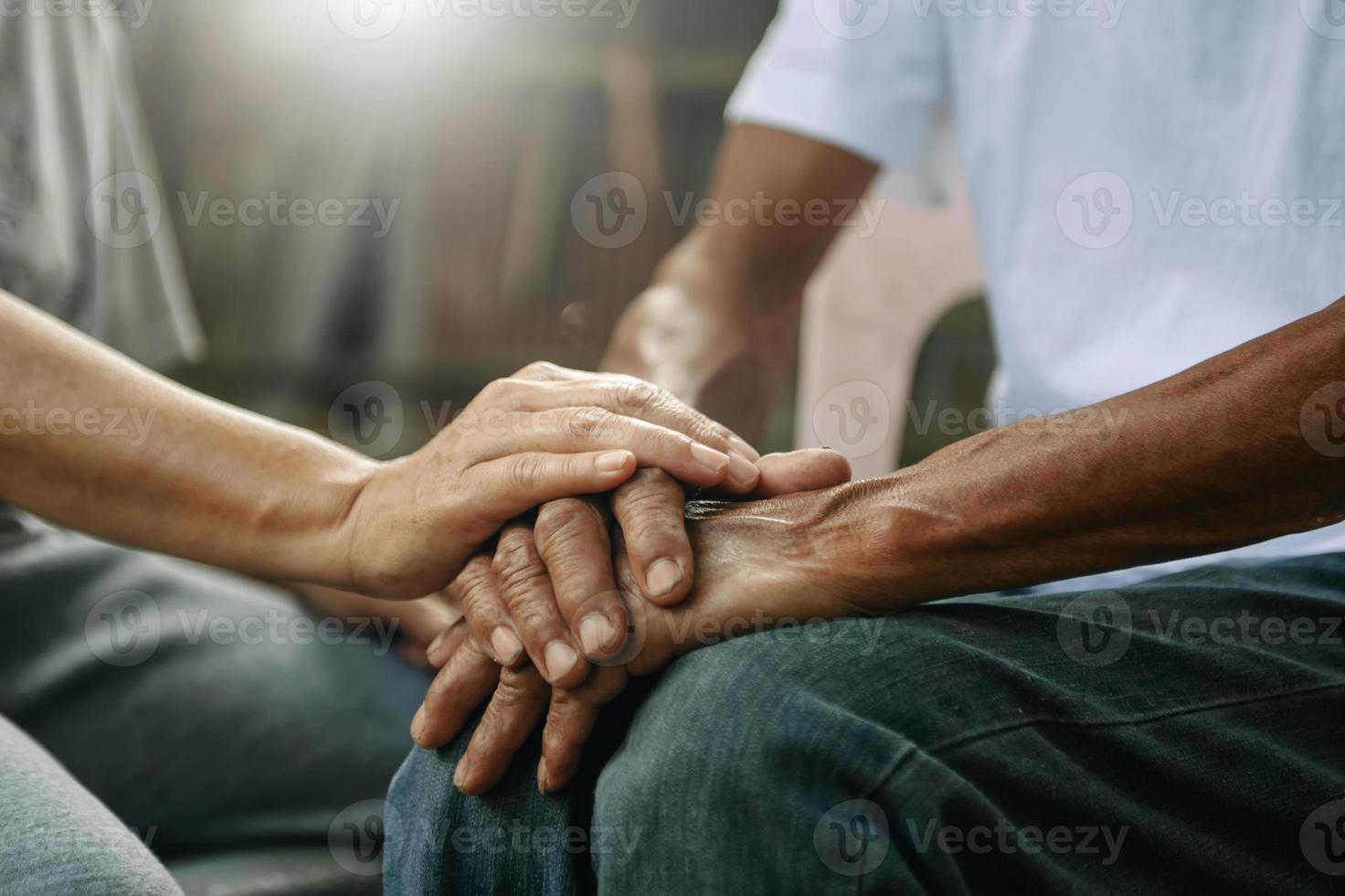 handen van de oud Mens en een vrouw hand- Aan de hout tafel foto