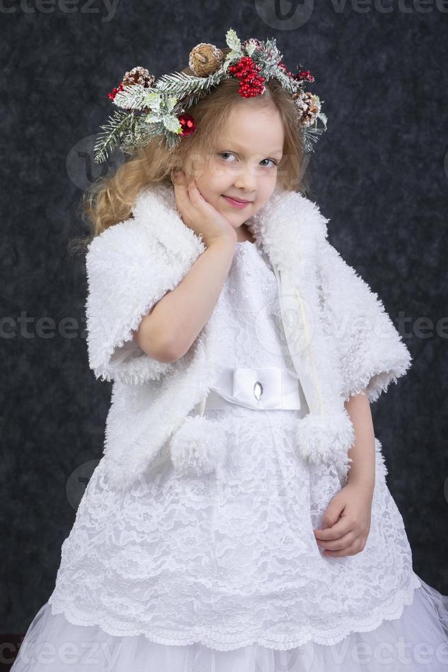 mooi weinig meisje in een wit jurk met een Kerstmis krans Aan haar hoofd. Kerstmis kind. foto