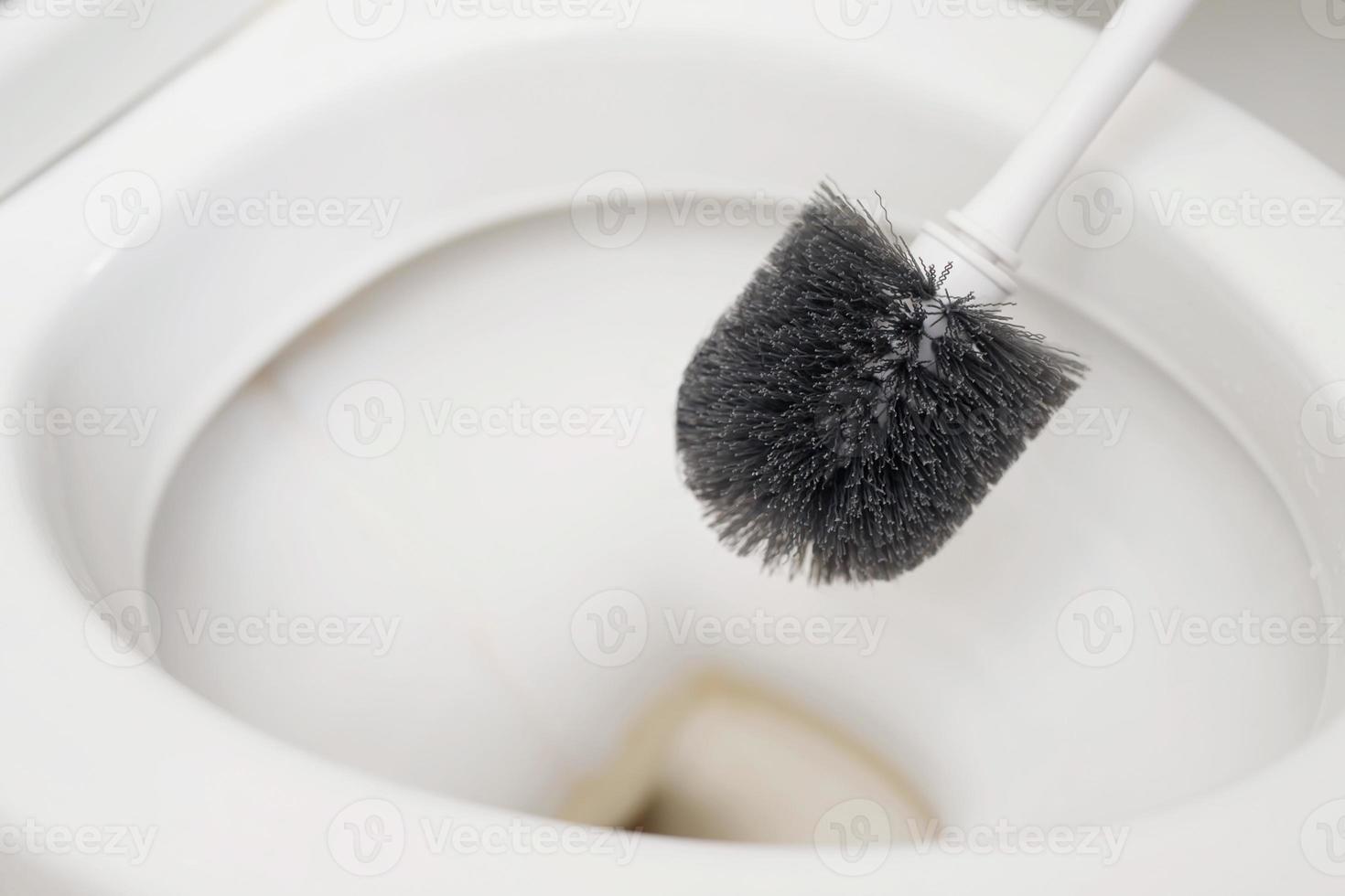 een huisvrouw is gebruik makend van een borstel naar schoon de toilet foto