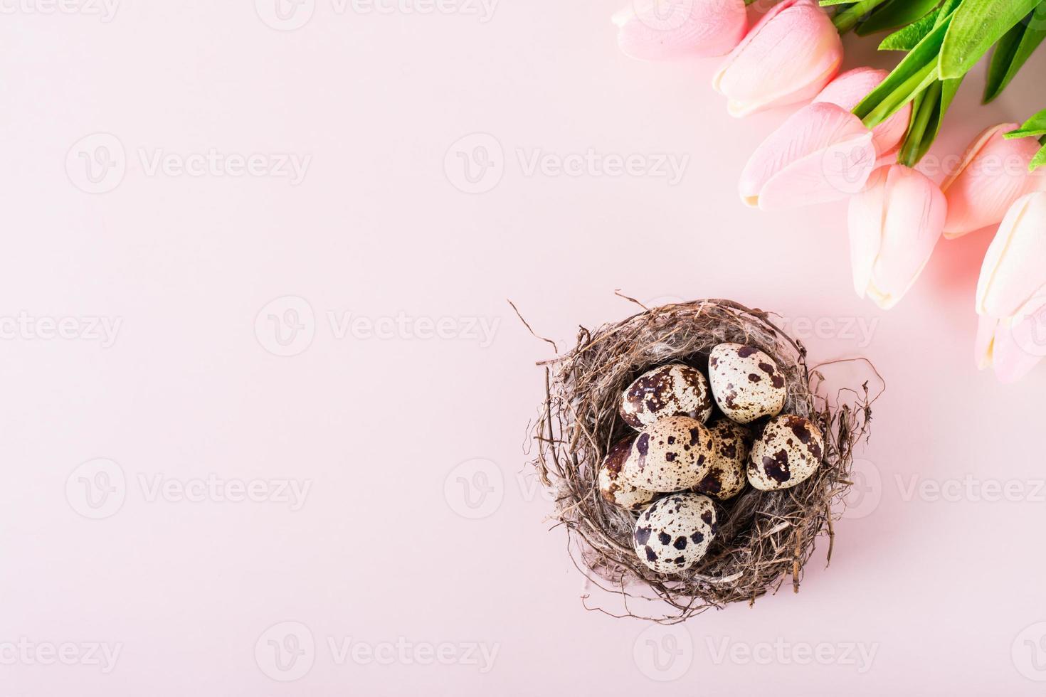 gelukkig Pasen kwartel eieren in natuurlijk nest en boeket van bloemen Aan roze achtergrond top visie foto