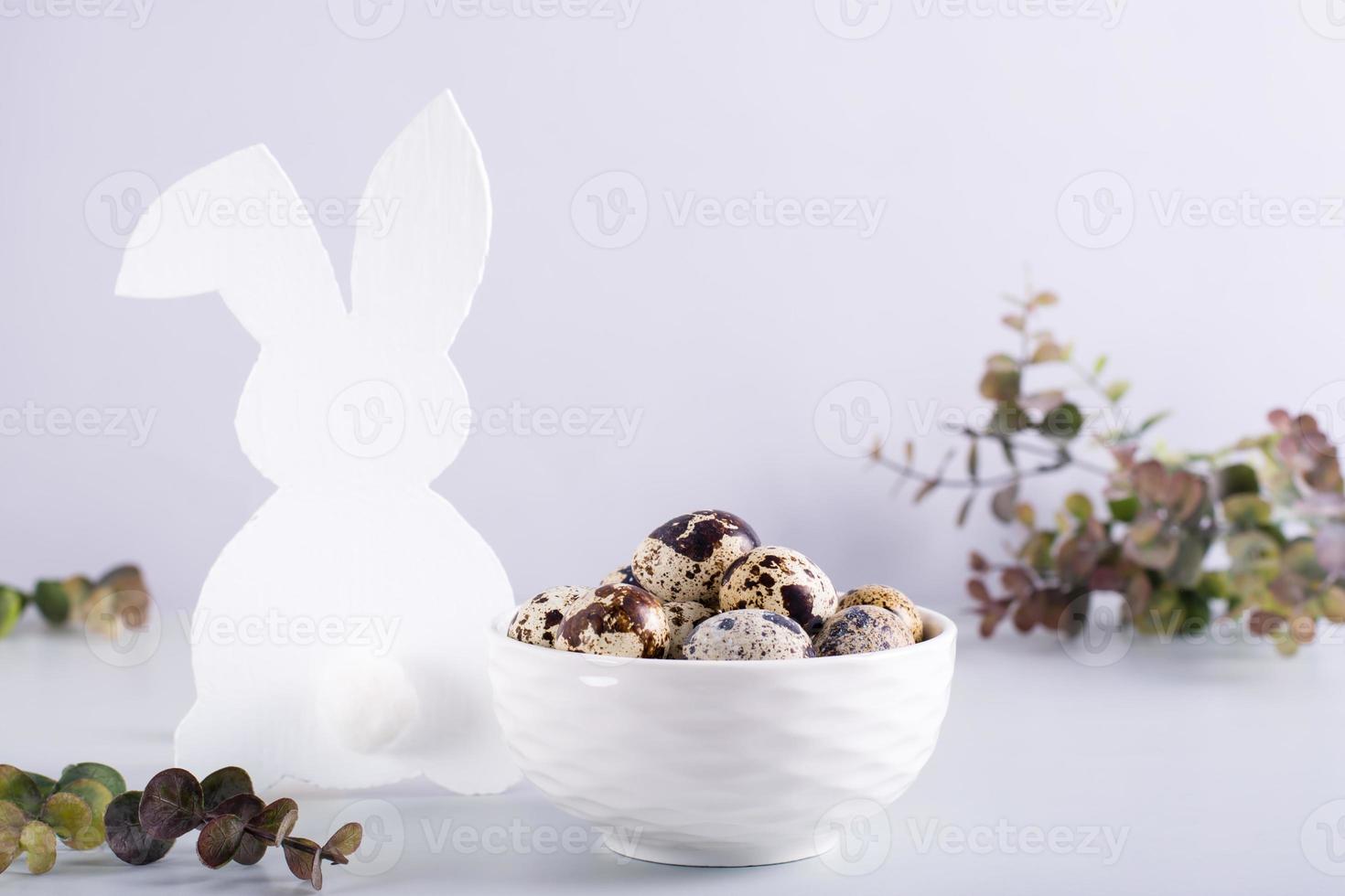 een kom van kwartel eieren en een wit konijn Aan de tafel voor een gelukkig Pasen. foto