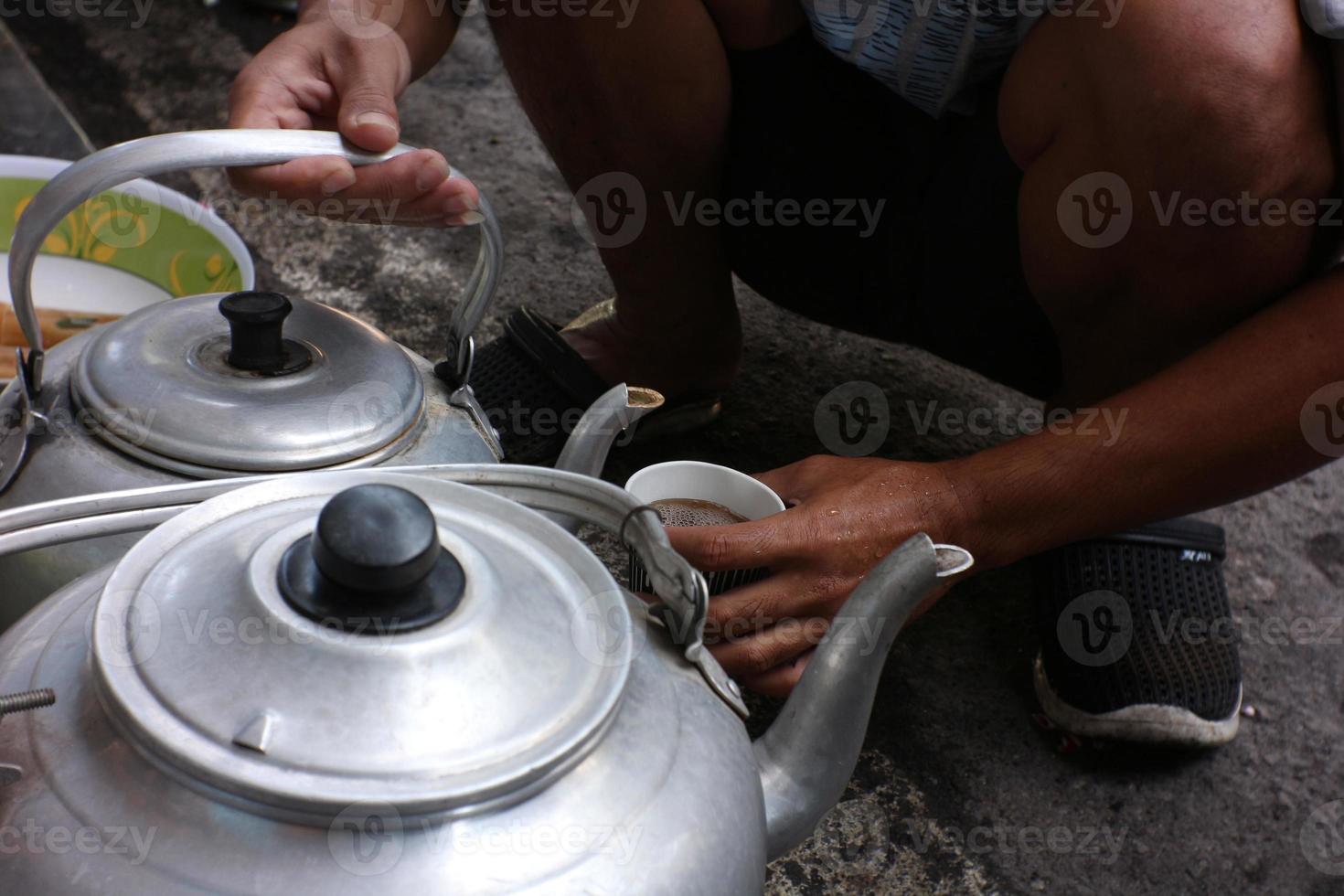 gieten warm thee water in een wit kop gedurende dorp schoonmaken werk foto