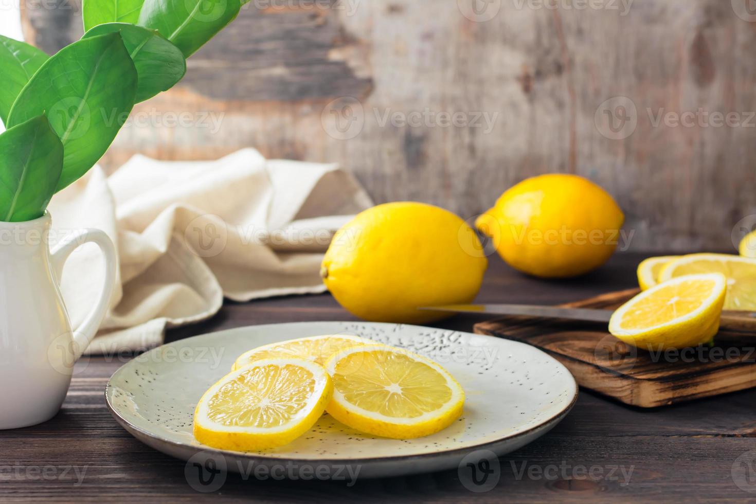 gesneden rijp citroenen Aan een bord en Aan een houten snijdend bord Aan de tafel. biologisch voeding, bron van vitamines. foto