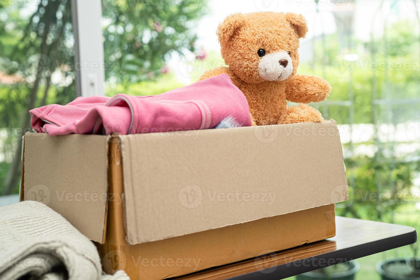 bijdrage doos met gebruikt kleren en pop Bij huis naar ondersteuning helpen voor arm mensen in de wereld. foto