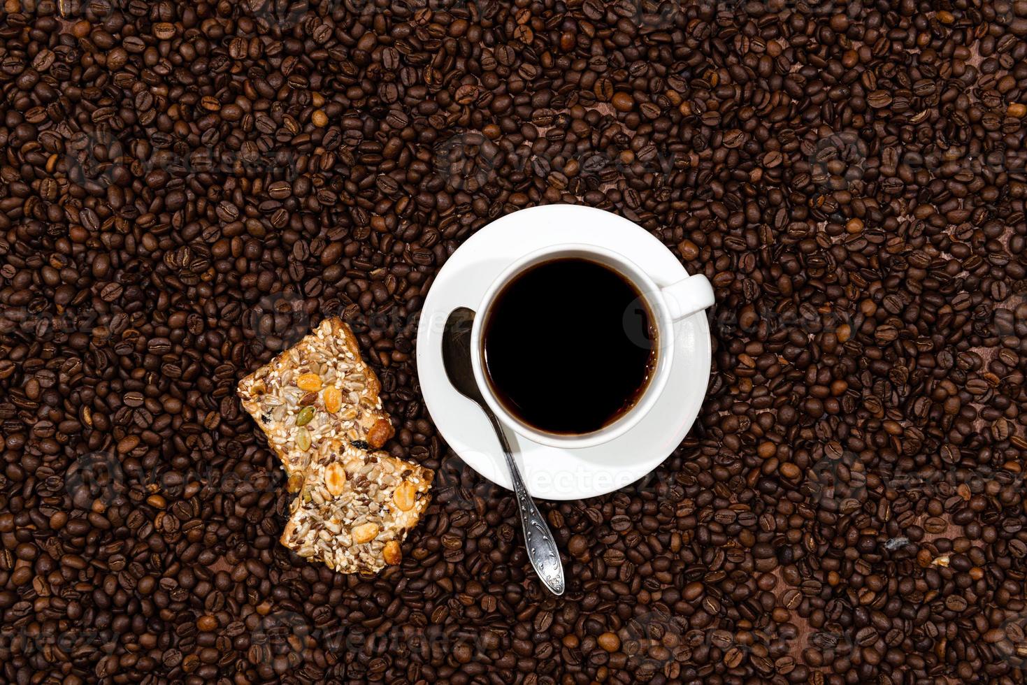 witte koffiemok en koekjes op de achtergrond van koffiebonen foto