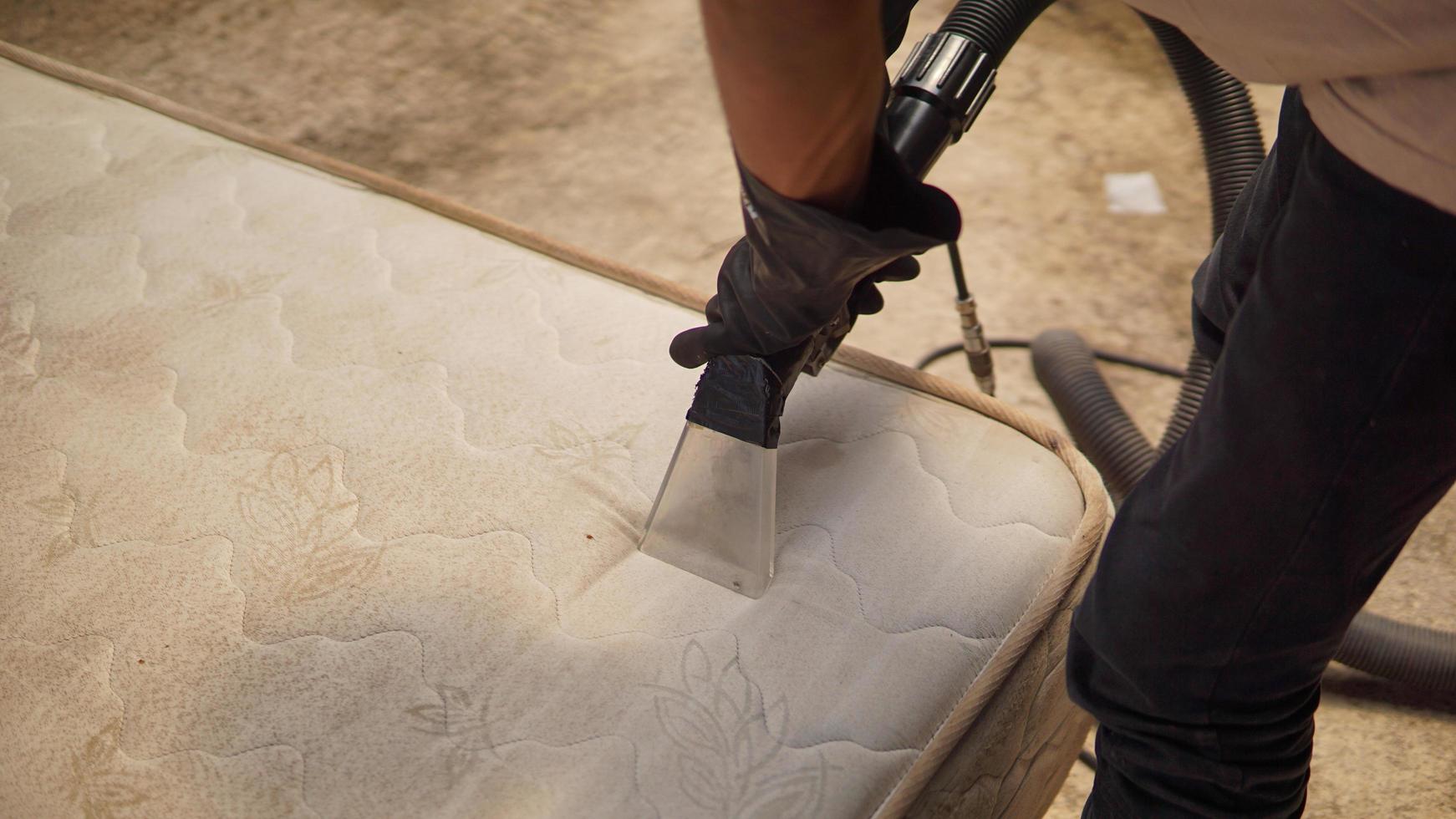 dichtbij omhoog van een man's handen in zwart handschoenen werken schoonmaak sofa foto