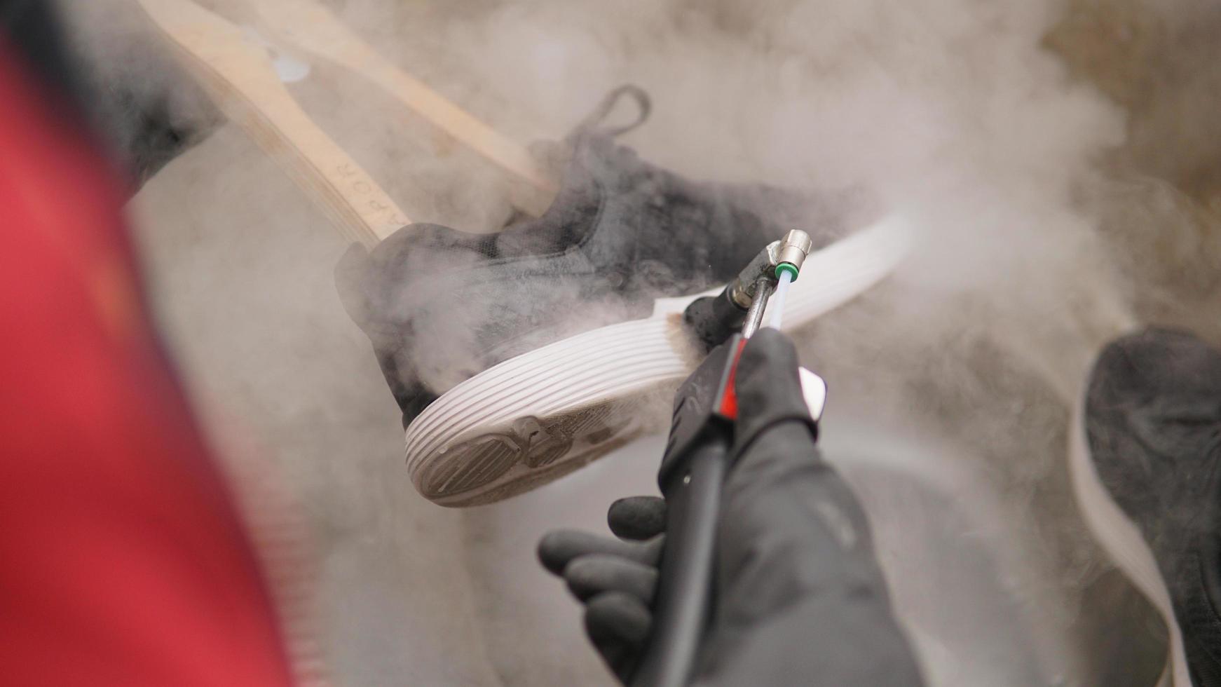 een schoen wezen gewassen gebruik makend van een waterdamp stoom- schoonmaakster foto