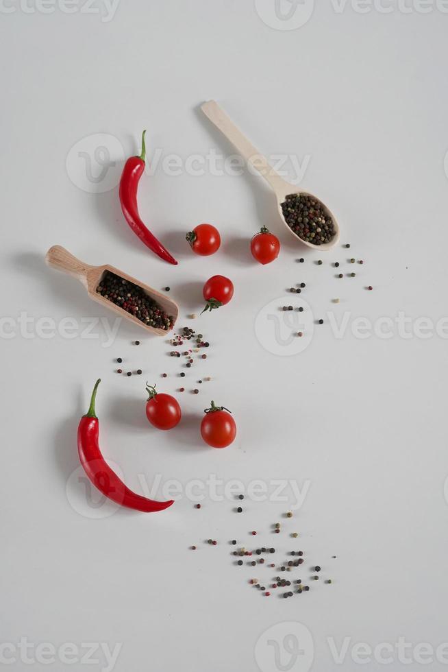 kers tomaten, rood heet Chili peper, geurig zwart peper erwten Aan een wit achtergrond. achtergrond met specerijen. vlak leggen, kopiëren ruimte foto