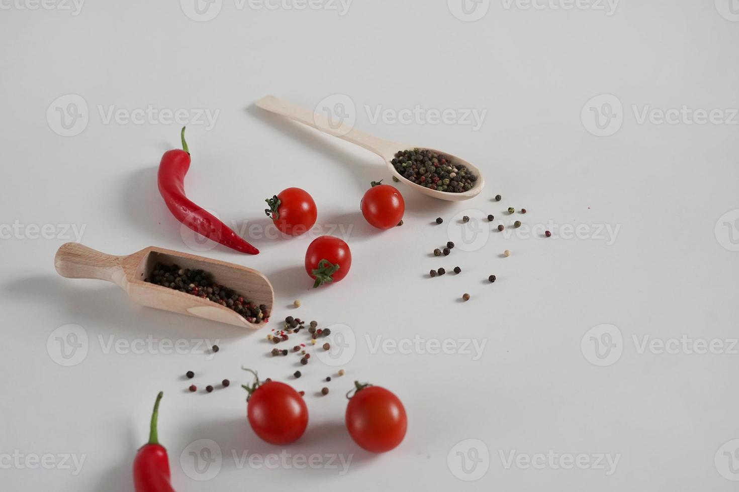 kers tomaten, rood heet Chili peper, geurig zwart peper erwten Aan een wit achtergrond. achtergrond met specerijen. vlak leggen, kopiëren ruimte foto