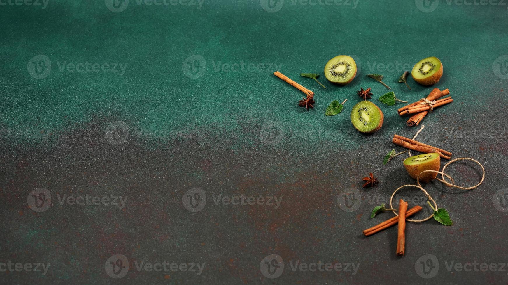 plakjes van vers, sappig kiwi Aan een groen achtergrond. versierd met kaneel stokken, badyan, munt bladeren. fruitig versierd achtergrond foto