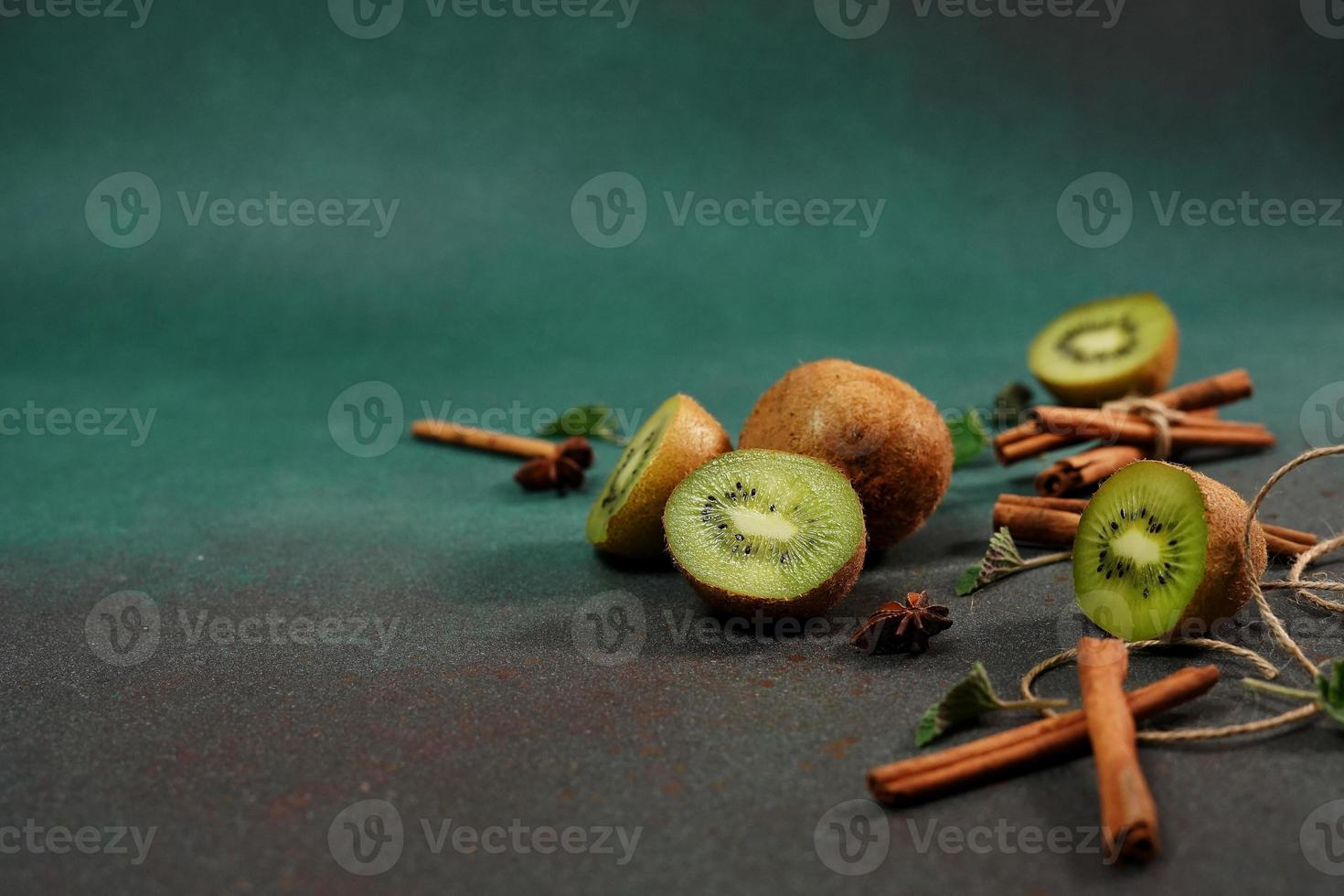plakjes van vers, sappig kiwi Aan een groen achtergrond. versierd met kaneel stokken, badyan, munt bladeren. fruitig versierd achtergrond foto