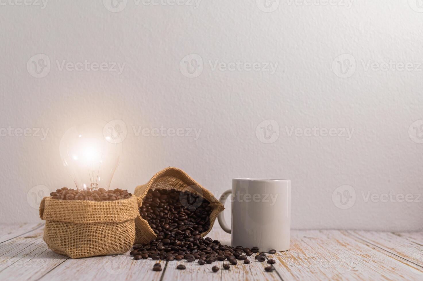 een koffiemok met zakken koffiebonen en een gloeilamp die energie uitstraalt op een houten tafel foto