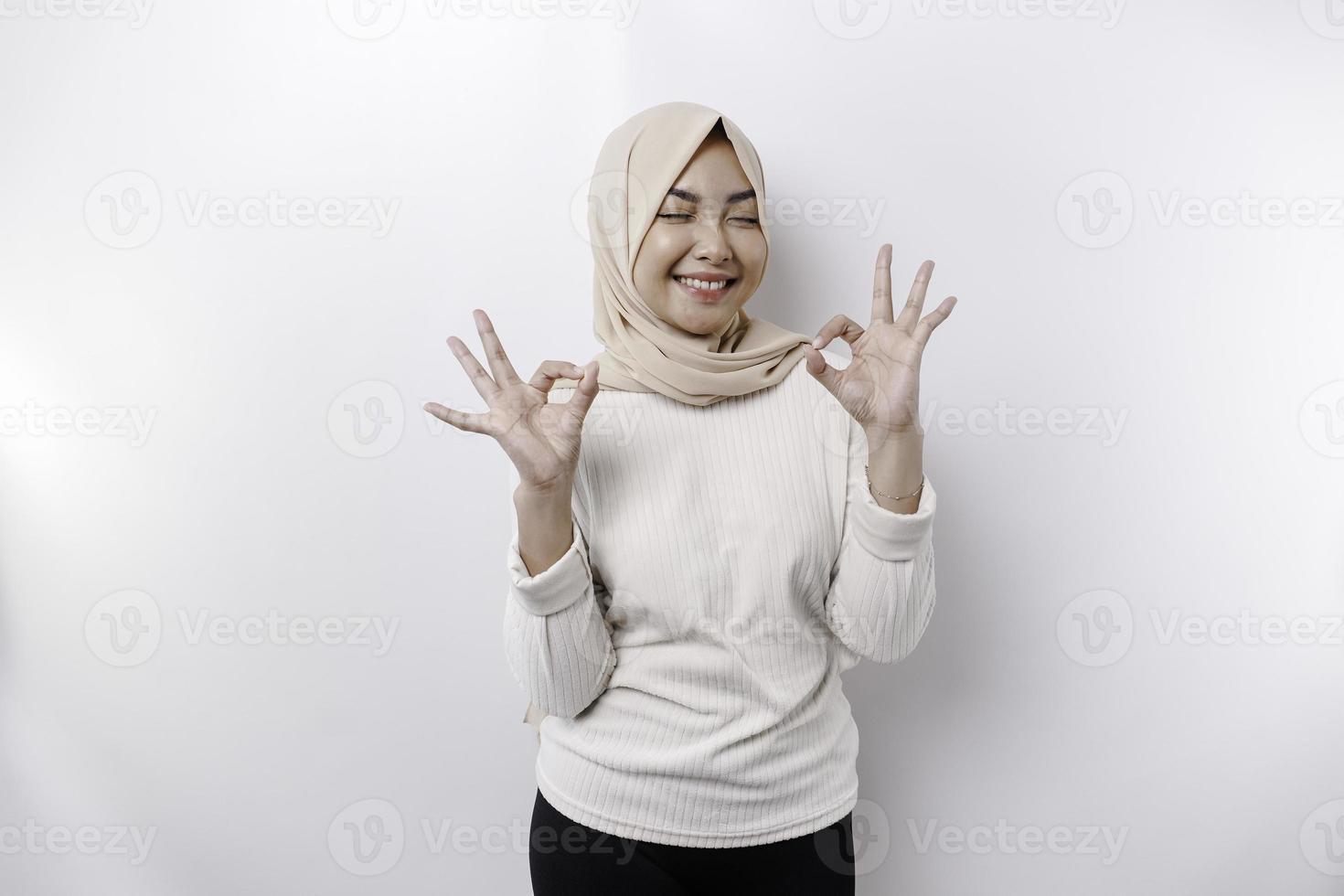 een glimlachen Aziatisch moslim vrouw, geven een OK hand- gebaar geïsoleerd over- wit achtergrond foto