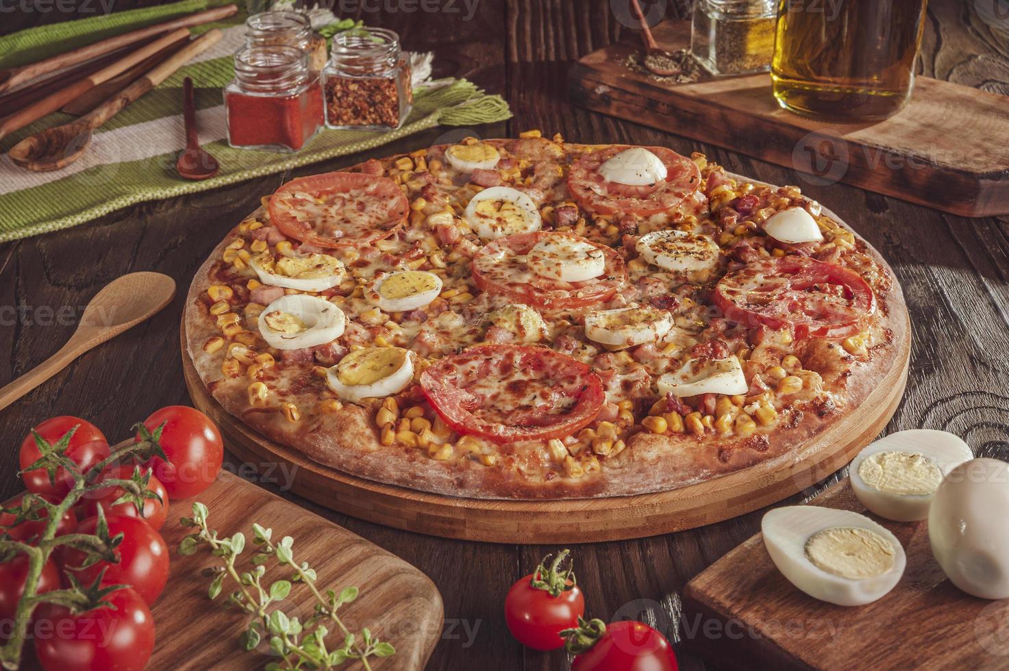 braziliaanse pizza met mozzarella, maïs, spek, eieren, tomaat en oregano foto