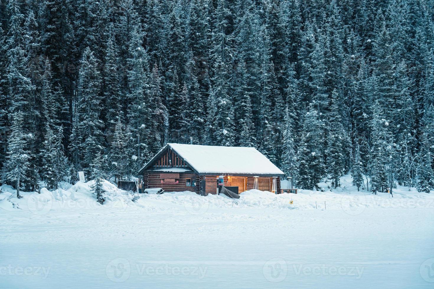 besneeuwd houten huisje gloeiend in pijnboom Woud Aan meer louise in wintertijd Bij banff nationaal park foto