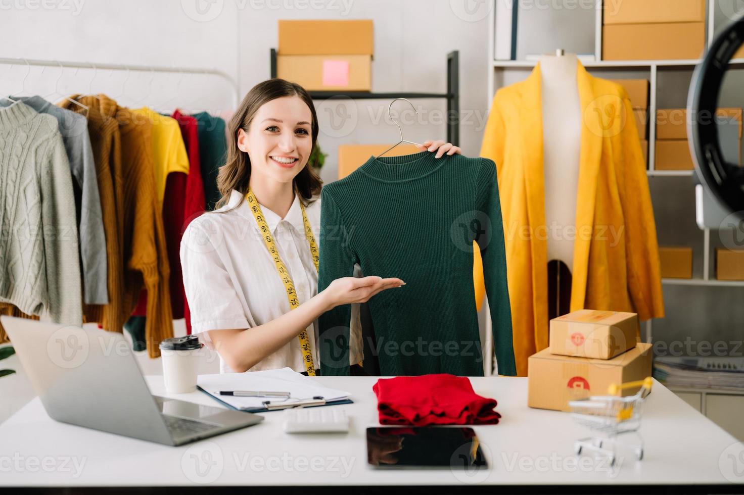 Aziatisch kleermaker vrouw werken Aan kleren in maatwerk atelier. mooi jong vrouw mode ontwerper glimlach en na succes in studio foto