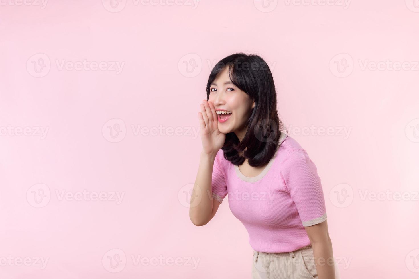 portret mooi jong Aziatisch vrouw uitdrukking yel schreeuw aankondigen nieuws van communicatie bericht of roepen luid stem met hand- naast mond gebaar geïsoleerd Aan roze pastel achtergrond. foto