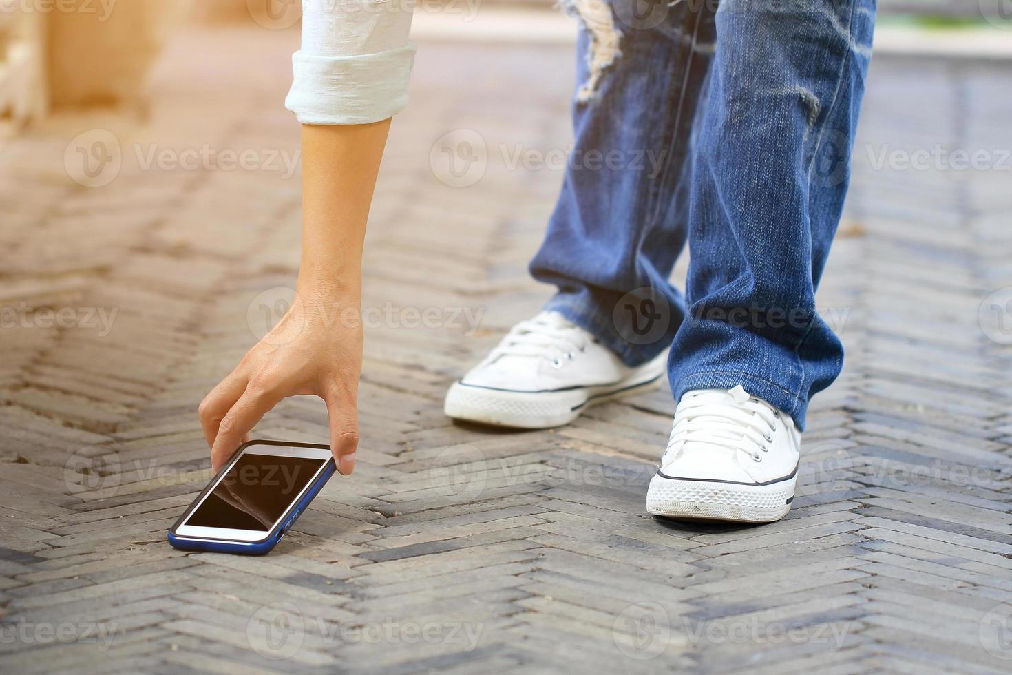 vrouw oppakken van een smartphone op de grond foto