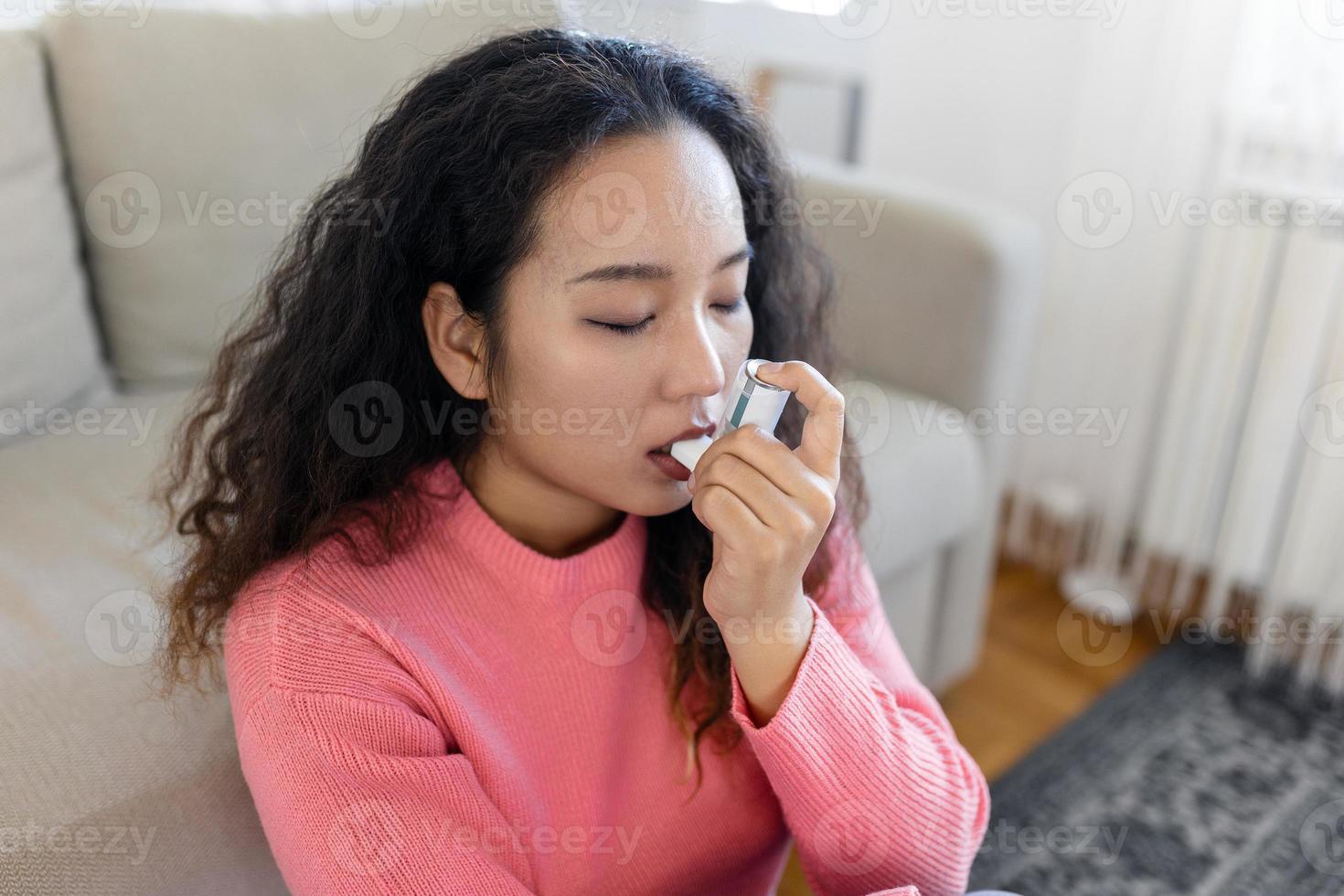 Aziatisch vrouw gebruik makend van inhalator terwijl lijden van astma Bij huis. jong vrouw gebruik makend van astma inhalator. detailopname van een jong Aziatisch vrouw gebruik makend van astma inhalator Bij huis. foto