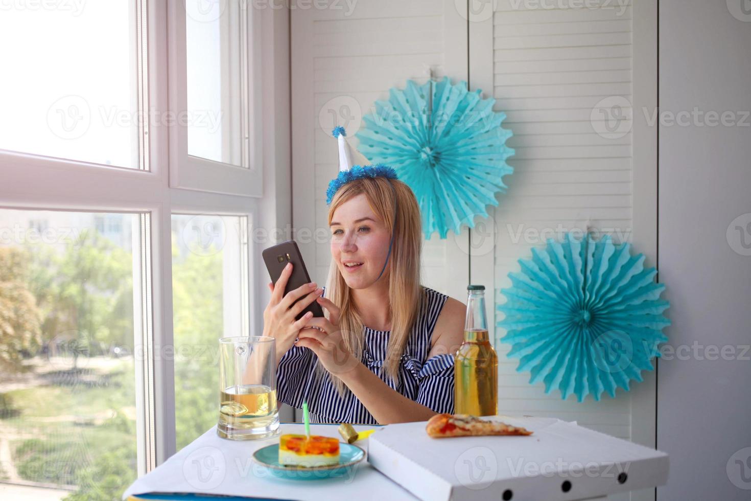 mooi vrouw Holding een telefoon in haar handen. viert zijn verjaardag over- de internet in quarantaine tijd. foto