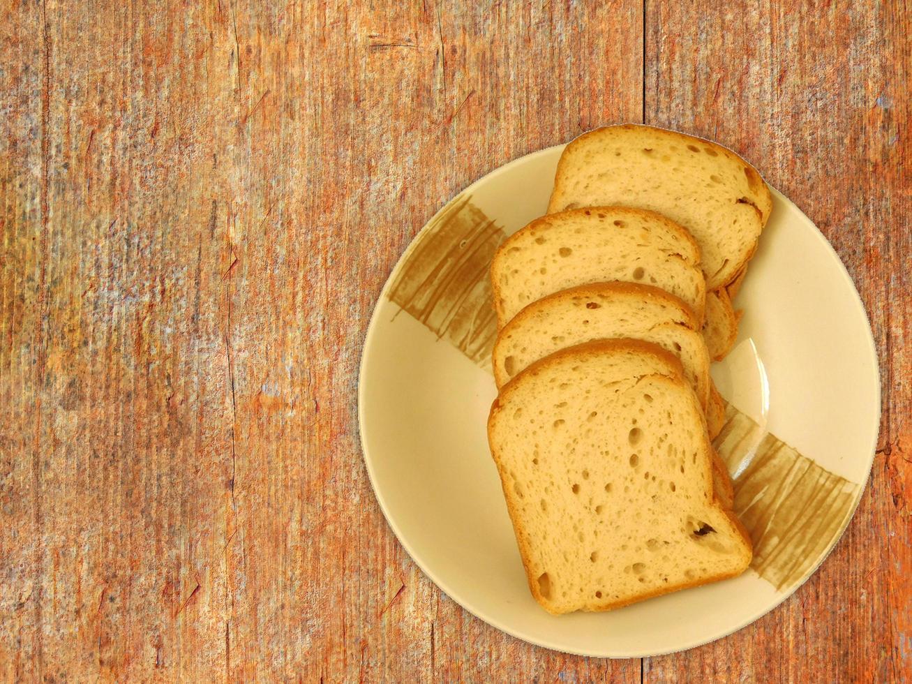 gesneden brood op een keramische plaat op een houten tafel achtergrond foto