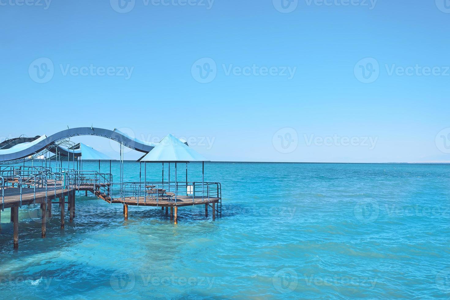 azuurblauw water met pier onder blauwe hemel foto