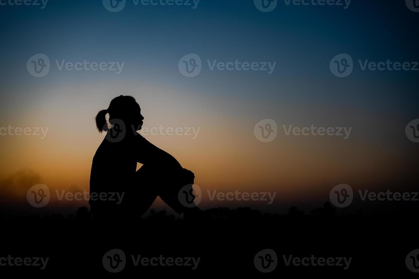 silhouet van een vrouw ga zitten met zo verdrietig in de zonsondergang. foto