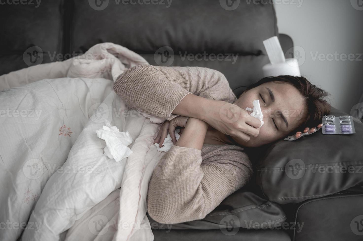 Aziatische zieke vrouw zit op de bank, blijf thuis, de vrouw voelde zich slecht, wilde gaan liggen en rusten, hoge koorts foto