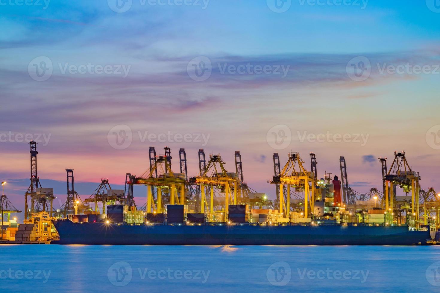 vrachtschip dat lading laadt bij laaddok op schemertijd. foto