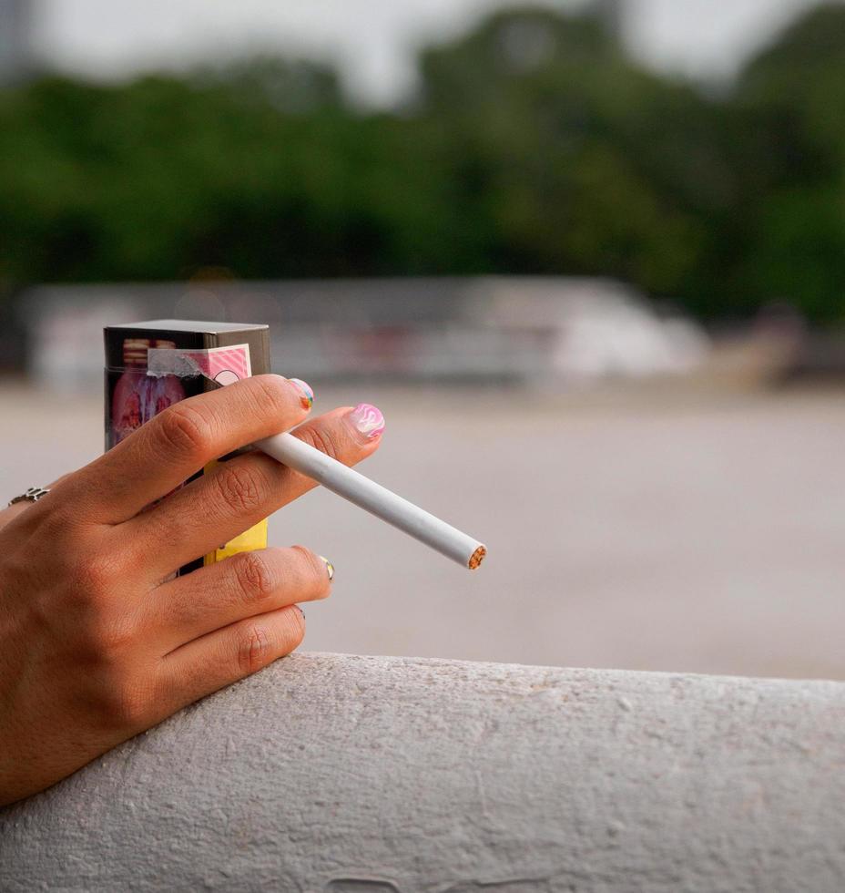 detailopname hand- vrouw tiener jong Azië een persoon vervelend een zwart overhemd houden roken sigaret wit kleur staand buitenshuis door de muur foto
