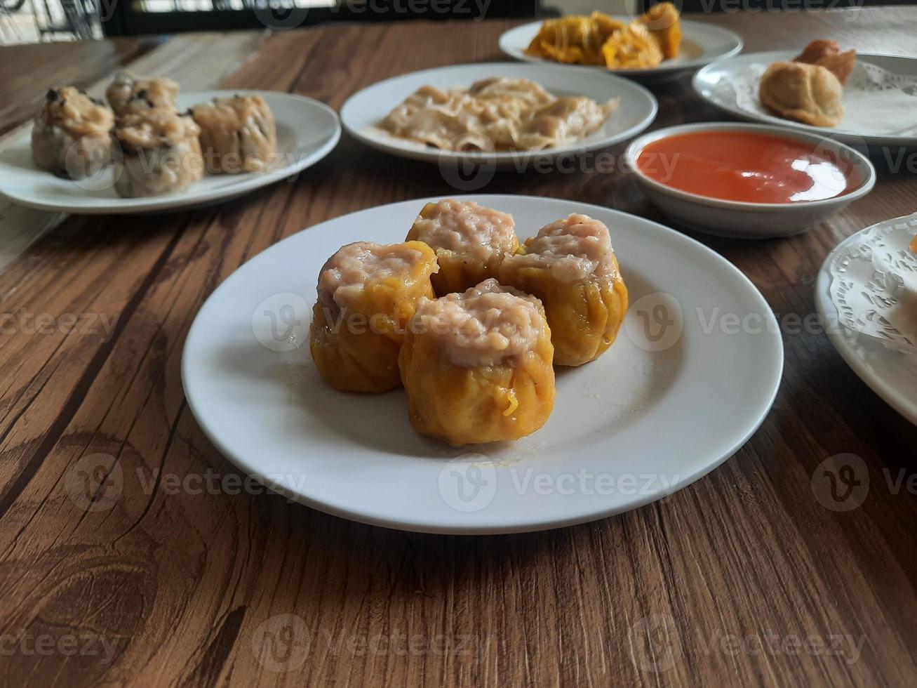 dimsum geserveerd warm Aan een wit bord met saus. foto