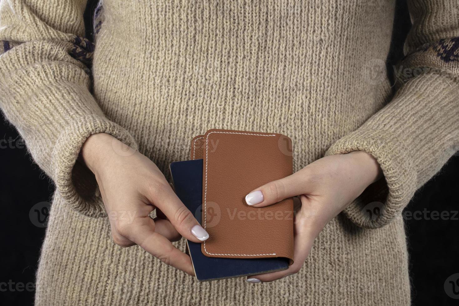 in vrouw handen Daar is een bruin handtas en een paspoort. foto