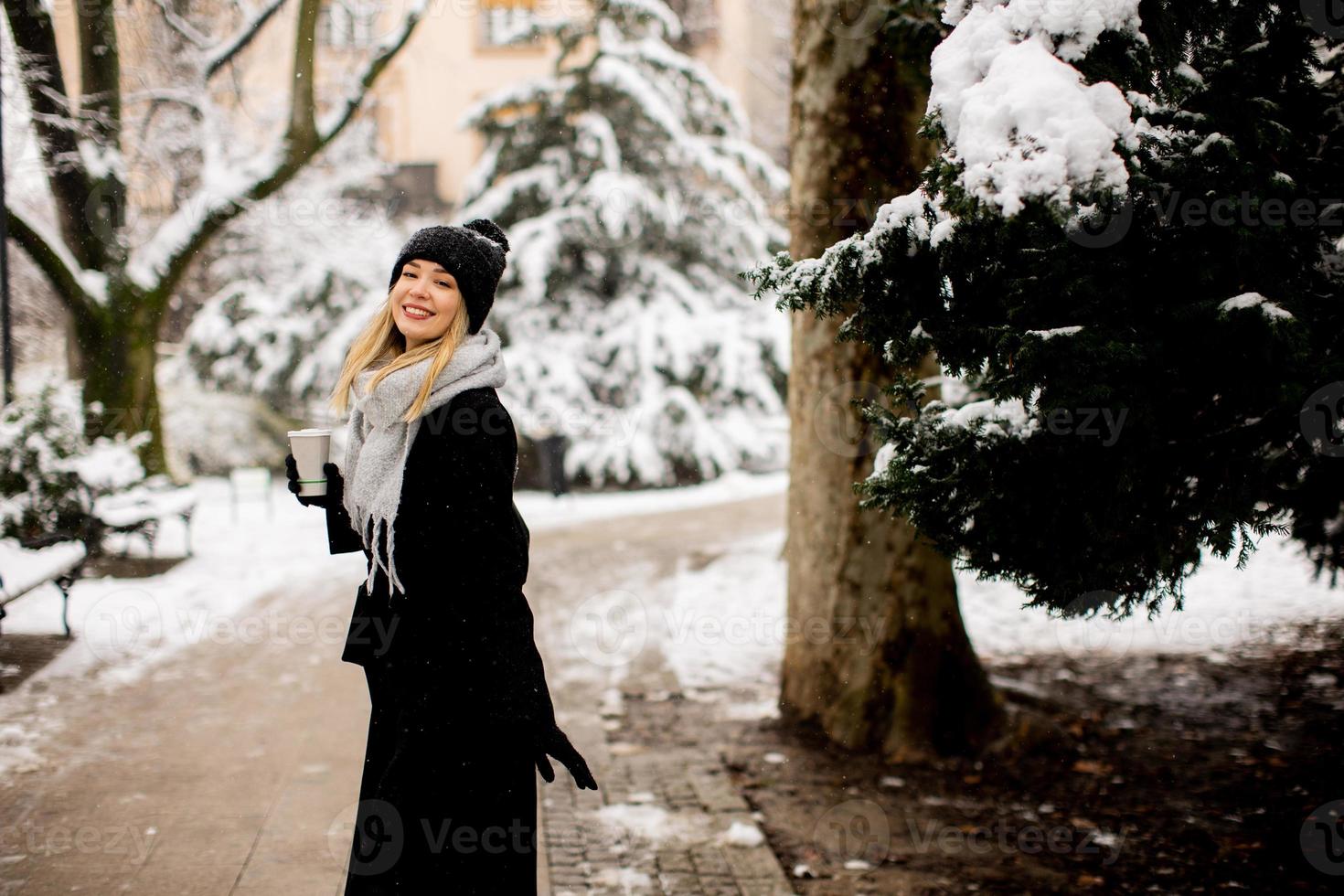 jong vrouw met warm kleren in verkoudheid winter sneeuw drinken koffie naar Gaan foto