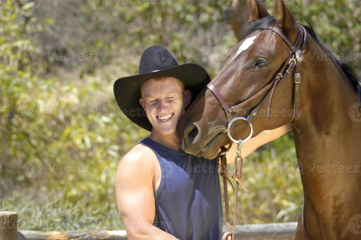 een knap cowboy krijgt een kus van zijn paard in een pret fotoshoot. foto