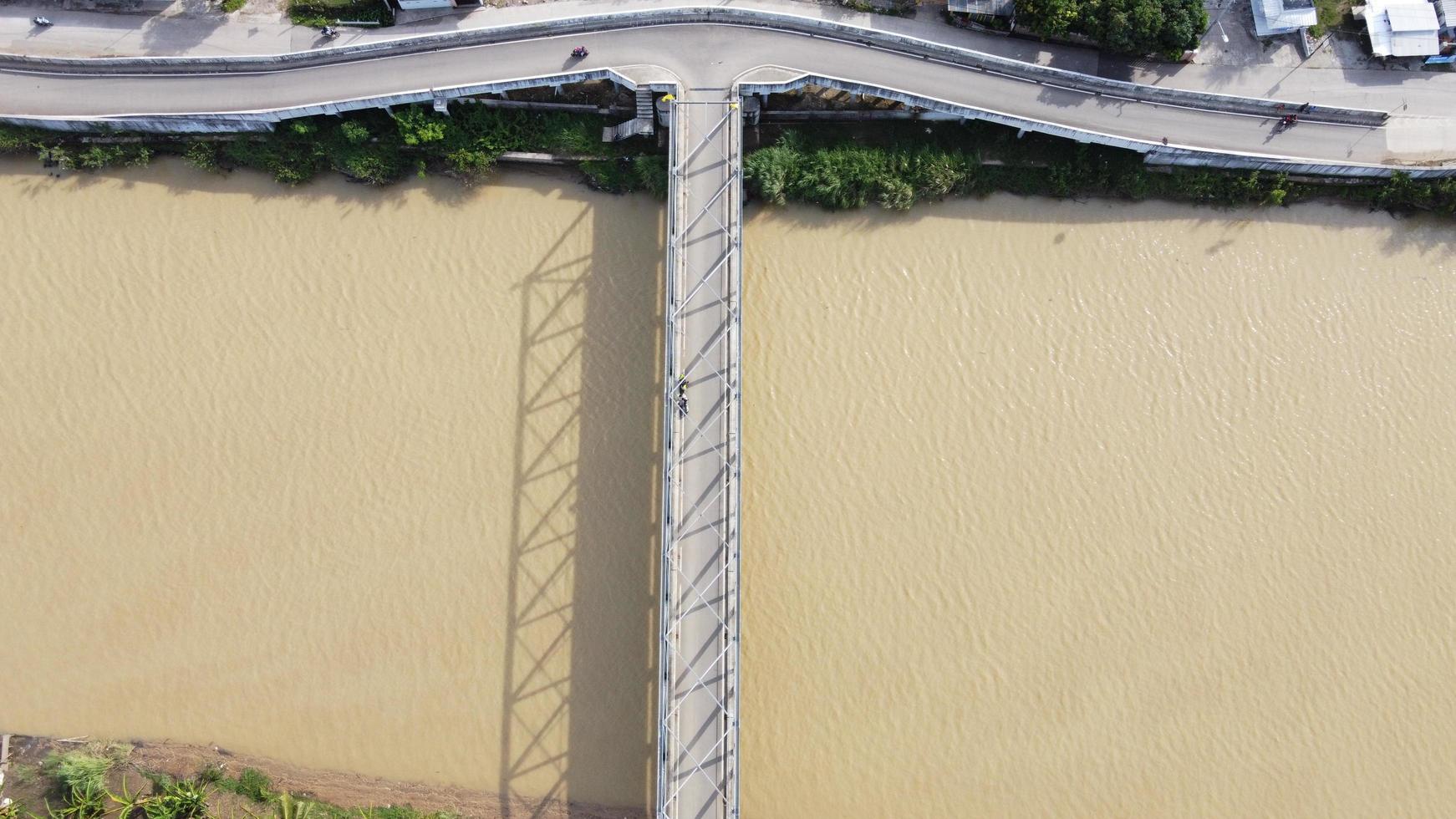 Bekasi, Indonesië 2021 - luchtfoto van een drone van een lange brug aan het einde van de rivier die twee dorpen met elkaar verbindt foto