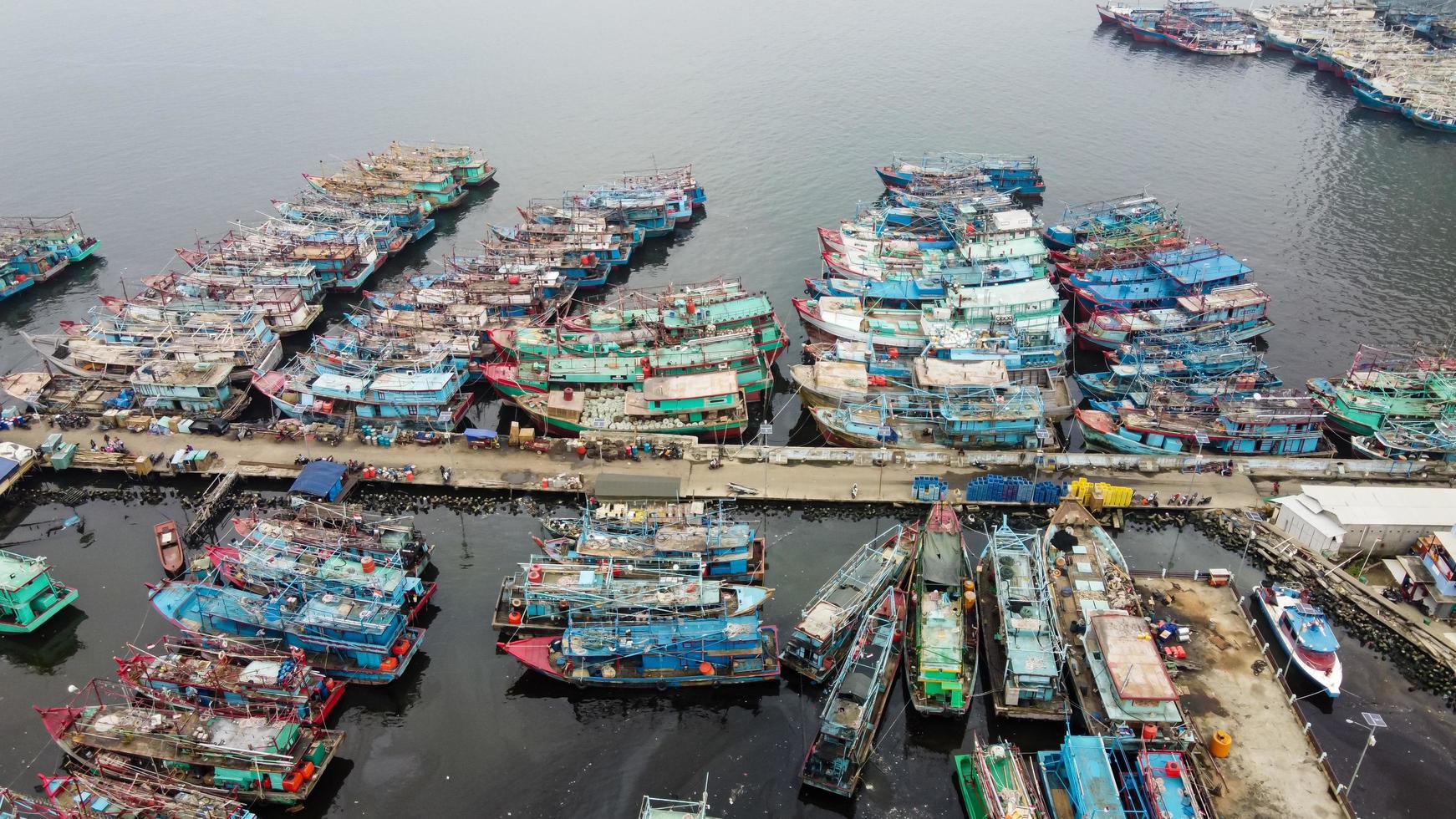 jakarta, indonesië 2021- luchtfoto drone-weergave van muara angke strand met houten boten die naast de pier leunen foto