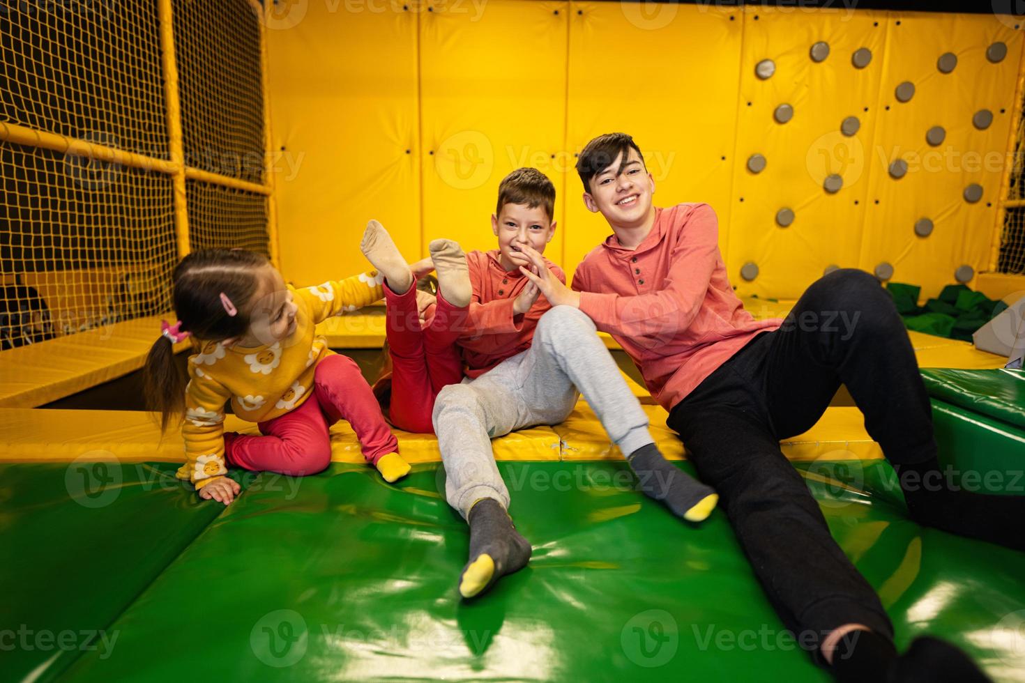 kinderen samen zitten Bij speelplaats park en geven hoog vijf elk ander. zussen en broers in actief vermaak. foto