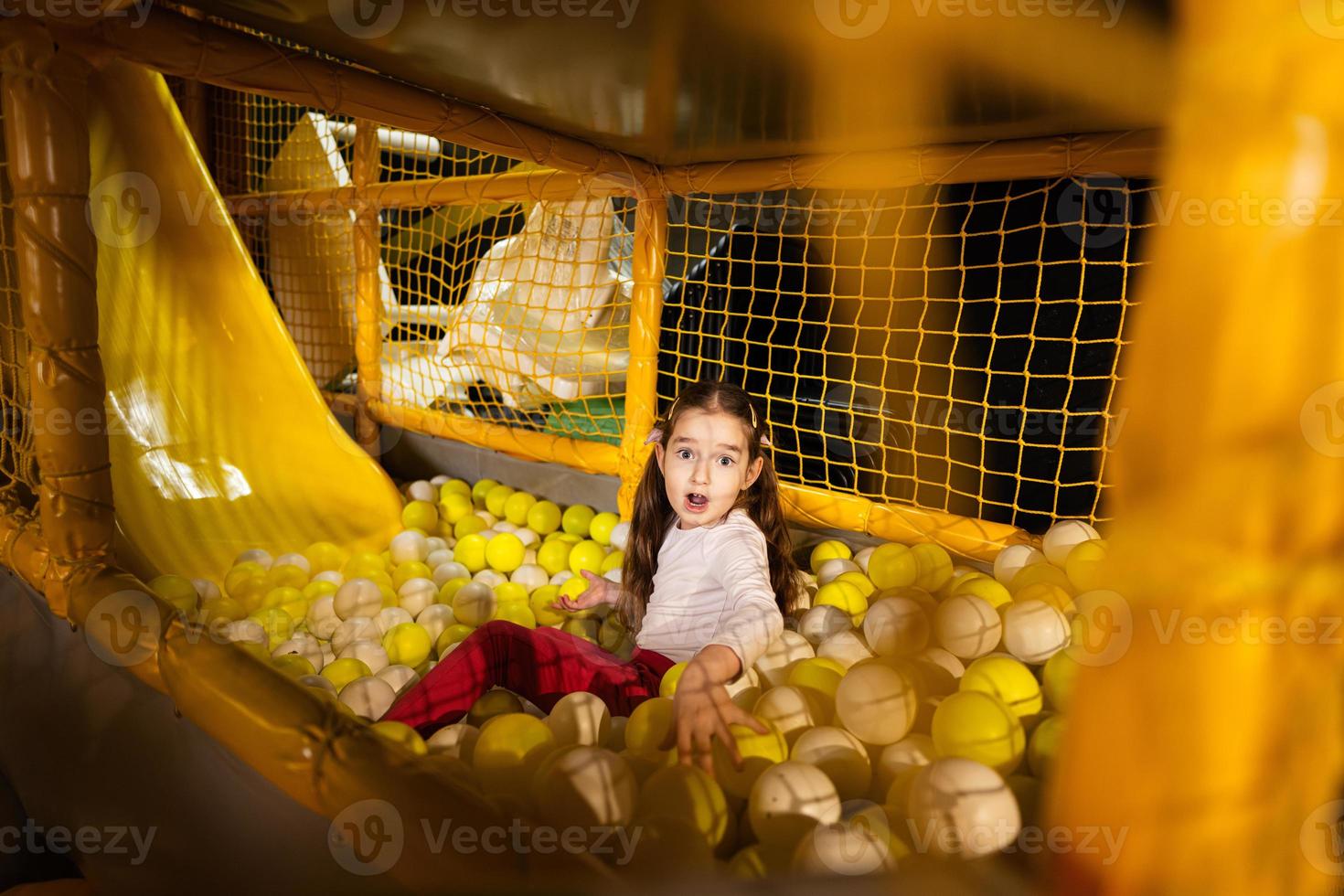 weinig meisje Speel met gekleurde ballen Bij geel speelplaats park in actief vermaak. foto