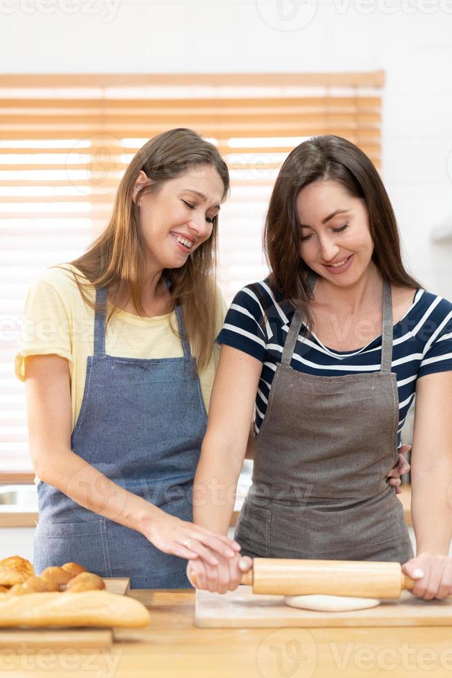 twee Kaukasisch Dames Koken pizza samen in de keuken. de concept van huis gekookt voedsel en lgbt verhoudingen. familie en verscheidenheid concept. lgbt liefde. foto